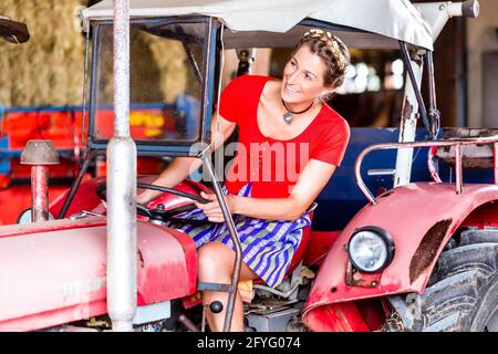 Femme avec robe Dirndl bavarois de la conduite du tracteur Banque D'Images