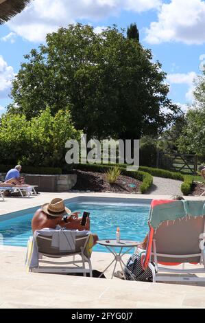 les gens se détendent dans des chaises longues près d'une piscine Banque D'Images