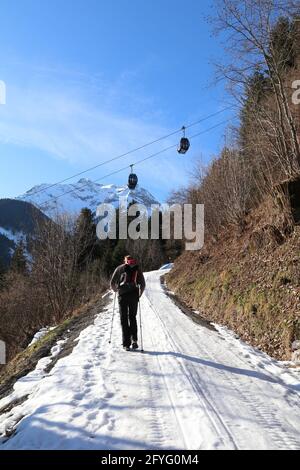 un seul homme randonnée sur un sentier enneigé sous les téléphériques