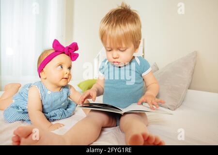 Bébé garçon lit le livre à la petite fille de bébé Banque D'Images