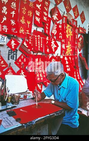 Singapour. Un vieil homme peint des signes calligraphiques pour les célébrations du nouvel an chinois. Banque D'Images