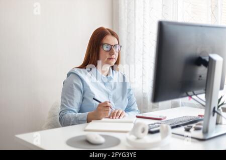 Femme tenant le stylo à la main sur le bloc-notes à la maison, écrit des objectifs, des plans, faire à faire et liste de souhaits sur le bureau, travaillant à la maison bureau. Banque D'Images