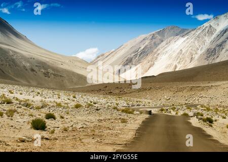 Une route en béton vers de belles montagnes rocheuses et ciel bleu avec des sommets de l'Himalaya, Leh, Ladakh, Jammu et Cachemire, Inde Banque D'Images