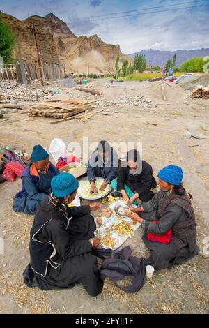 Mulbekh, Ladakh, Inde - 2 septembre 2014 : femmes tribales Ladakhi dans des robes traditionnelles coupant des légumes pour préparer la nourriture pour le festival religieux Banque D'Images