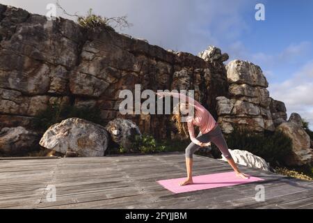 Bonne femme caucasienne pratiquant le yoga debout sur le pont s'étirant cadre rural de montagne Banque D'Images