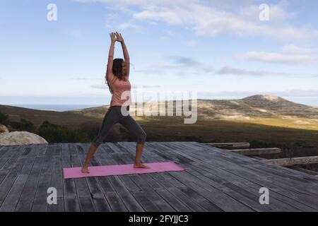 Bonne femme caucasienne pratiquant le yoga debout sur le pont s'étirant cadre rural de montagne Banque D'Images