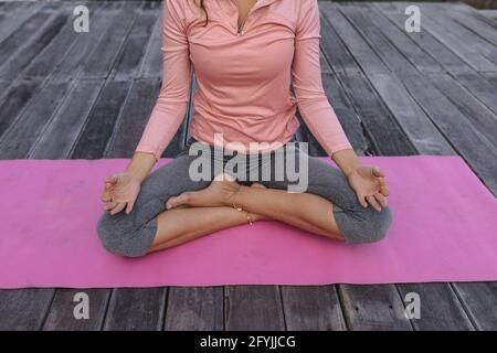 Section basse de la femme caucasienne pratiquant le yoga assis sur le pont en position lotus Banque D'Images