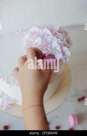 Femme décorant un gâteau éponge de crème de beurre avec un macaron rose Banque D'Images