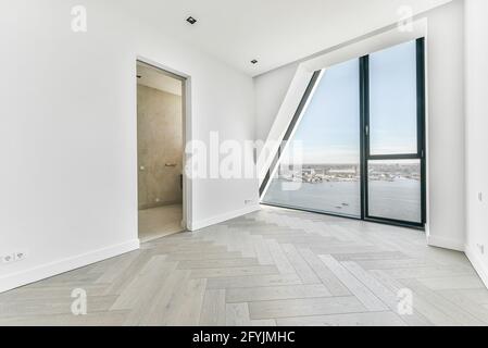 Intérieur non meublé avec parquet et murs blancs et fenêtre murale dans un appartement de luxe Banque D'Images