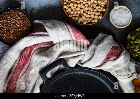 Vue en hauteur d'une casserole et d'une serviette de thé avec des pois chiches frais, des graines de lin, des graines de citrouille et du sel Banque D'Images