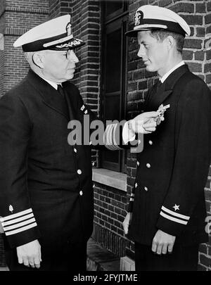 Le lieutenant John F. Kennedy reçoit la Médaille de la Marine et du corps des Marines pour son héroïsme au sauvetage des membres de l'équipage du PT-109; photographie originale prise le 11 juin 1944. Capitaine Frederick L. Conklin, commandant de l'hôpital naval de Chelsea; John F. Kennedy. Hôpital naval de Chelsea, Chelsea, Massachusetts. Banque D'Images