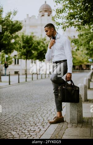 Un beau jeune homme d'affaires afro-américain attende un taxi sur une rue Banque D'Images