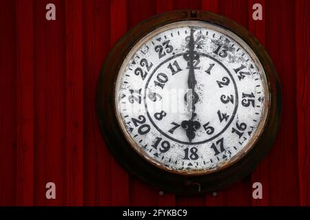 Ancienne horloge sur un mur en bois rouge. Banque D'Images