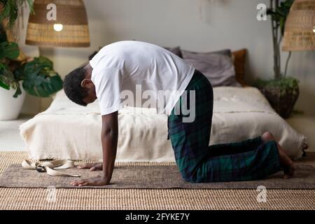 Sportif musclé jeune homme africain s'entraîner, yoga, pilates, entraînement physique, faire la pose de chat Banque D'Images