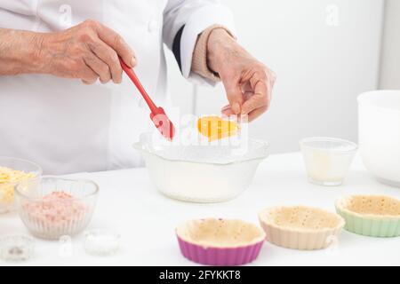 Femme senior préparant la garniture pour un délicieux fromage et tartelet au jambon Banque D'Images