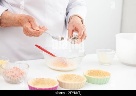 Femme senior préparant la garniture pour un délicieux fromage et tartelet au jambon Banque D'Images