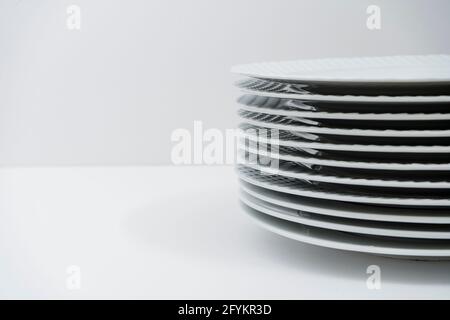 Ensemble de plats blancs empilés lavés sur une table blanche. Banque D'Images