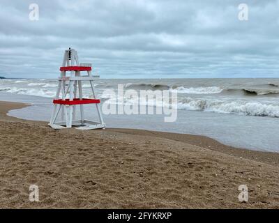 Chaise de maître nageur vide sur Tower Beach, le long de la côte de l'Illinois du lac Michigan, lors d'une journée de tempête alors que les vagues s'écrasont le long de la rive en arrière-plan. Banque D'Images