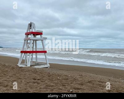 Chaise de maître nageur vide sur Tower Beach, le long de la côte de l'Illinois du lac Michigan, lors d'une journée de tempête alors que les vagues s'écrasont le long de la rive en arrière-plan. Banque D'Images