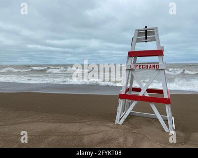 Chaise de maître nageur vide sur Tower Beach, le long de la côte de l'Illinois du lac Michigan, lors d'une journée de tempête alors que les vagues s'écrasont le long de la rive en arrière-plan. Banque D'Images