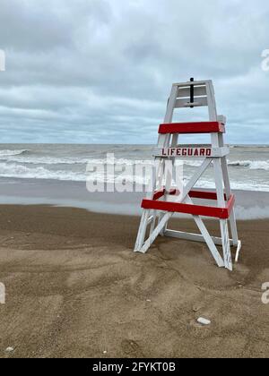 Chaise de maître nageur vide sur Tower Beach, le long de la côte de l'Illinois du lac Michigan, lors d'une journée de tempête alors que les vagues s'écrasont le long de la rive en arrière-plan. Banque D'Images