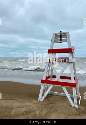 Chaise de maître nageur vide sur Tower Beach, le long de la côte de l'Illinois du lac Michigan, lors d'une journée de tempête alors que les vagues s'écrasont le long de la rive en arrière-plan. Banque D'Images