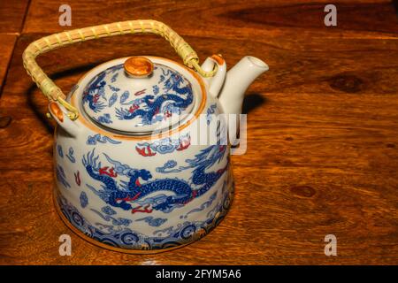 Un pot blanc en céramique avec motif dragon tout autour il a gardé sur une table en bois Banque D'Images