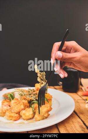 Cuisine péruvienne: Crevettes sautées aux herbes et à l'ail, table en bois, servies sur une assiette blanche, accompagnées de jus de maïs violet Banque D'Images