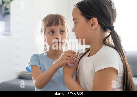 Enfant de neuf ans souffrant d'asthme allergique, inhalant son médicament à travers l'espaceur tout en regardant avec ses yeux fatigués Banque D'Images