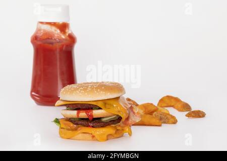 Double hamburger avec bacon, tranches de pommes de terre et bouteille de ketchup Banque D'Images
