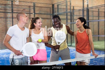 Heureux quatre partenaires hommes et femmes de padel tennis posant sur le court de tennis Banque D'Images