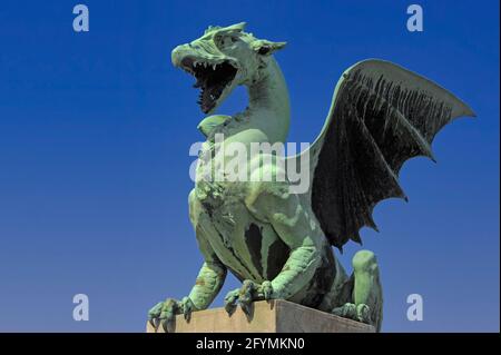 L'un des quatre dragons féroces avec des ailes étirées, des pieds clavetés et des fangs verts qui gardent le pont du Dragon au-dessus de la rivière Ljubljana, en Slovénie. Ils figurent parmi les sites les plus populaires de la ville, en partie à cause de la revendication (non prouvée) selon laquelle ils se désalissent ou se remuent la queue chaque fois qu'une vierge traverse le pont. Les monstres mythiques, faits à Vienne de cuivre, ont été conçus par l'architecte et ingénieur Jurij Zaninović pour le pont, qui a ouvert en 1901. Le dragon est l'emblème officiel de Ljubljana, qui se présente sur les armoiries et le drapeau de la ville et même sur les couvercles de trous d'homme municipaux. Banque D'Images