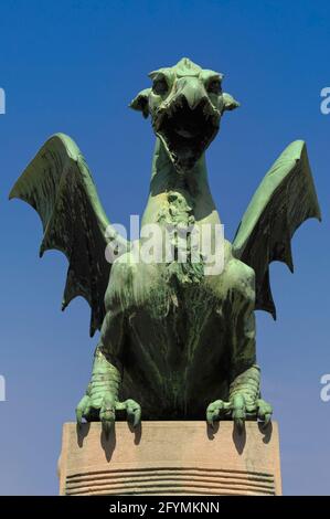 Bienvenue au pont du Dragon à Ljubljana, en Slovénie, dans l'un des quatre dragons de cuivre vert qui protègent la portée en béton armé de la rivière Ljubljana, ouvert en 1901. Les monstres mythiques font partie des sites les plus populaires de la capitale slovène, notamment pour leur prétendue capacité à remuer ou à pirer la queue chaque fois qu'une vierge traverse le pont. Le dragon est l'emblème officiel de Ljubljana, qui se présente sur les armoiries et le drapeau de la ville, et même sur les couvercles de trous d'homme municipaux. Banque D'Images