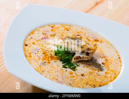 Soupe crémeuse traditionnelle de morue norvégienne avec légumes et légumes frais dans une assiette blanche Banque D'Images