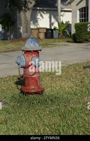 Plan vertical d'un poteau incendie rouillé sur une pelouse en face d'une maison Banque D'Images