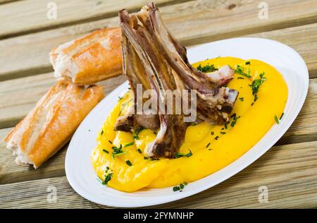 Le Pinnekjott est un plat traditionnel norvégien de fête de mouton sur os, servi avec une purée de chou-raquette et une baguette fraîchement cuite sur une table en bois Banque D'Images