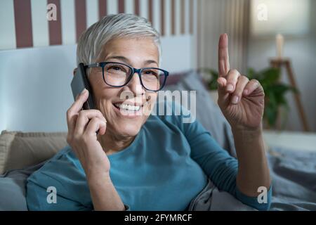 Femme mûre souriante parlant au téléphone Banque D'Images