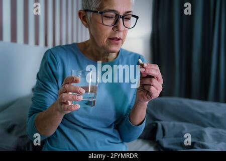 Femme prenant des pilules de mélatonine Banque D'Images