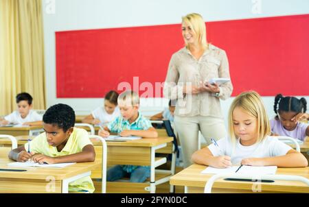 Groupe de préadolescents écoliers travaillant diligemment en classe, prenant des notes de la conférence des enseignants Banque D'Images