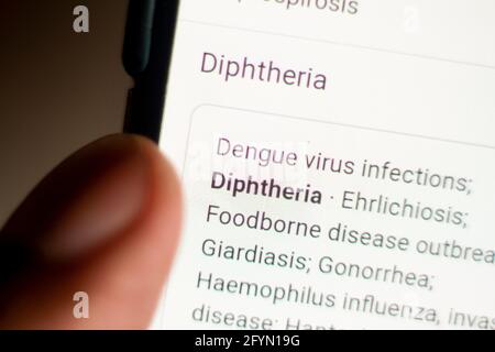 Diphtérie nouvelles sur le téléphone.téléphone mobile entre les mains. Mise au point sélective et aberrations chromatiques effets. Banque D'Images