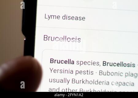 Brucellose nouvelles sur le téléphone.téléphone mobile entre les mains. Mise au point sélective et aberrations chromatiques. Banque D'Images