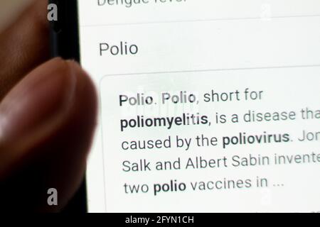 Polio nouvelles au téléphone.téléphone mobile entre les mains. Mise au point sélective et aberrations chromatiques. Banque D'Images