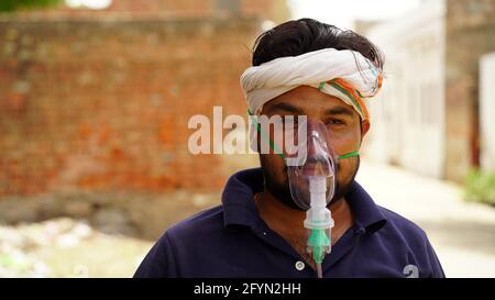 Jaipur, Inde - Mai 2021: Jeune homme attrayant avec masque d'oxygène regardant triste et inquiet à l'extérieur de l'hôpital. Portrait aérien d'une jeune personne, avec Banque D'Images