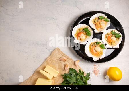 Vue de dessus noix de Saint-Jacques cuites au four avec caviar et sauce à l'ail crémeuse. Pétoncles, citron, ail, persil, beurre et sel. Recette pour la cuisson des pétoncles avec la cav Banque D'Images