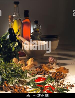 4 bouteilles de verre liquide coloré pilon et mortier herbes piments ail gingembre champignons poivre épices fond sombre bouteilles rétro-éclairé espace de copie Banque D'Images