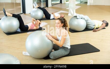 Portrait d'une fille positive effectuant un ensemble d'exercices avec pilates ballon pendant la classe de groupe dans le studio de fitness Banque D'Images