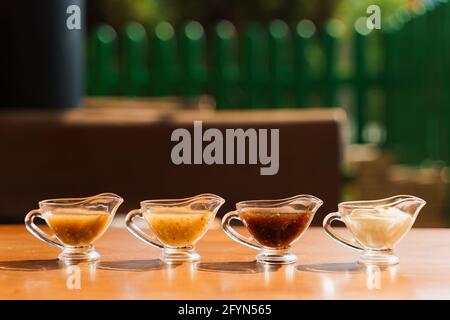 Assortiment de sauces en bol, moutarde, barbecue, mayonnaise et teriyaki, sur table en bois. Banque D'Images