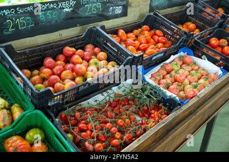 Boîtes avec des tomates mûres divers in grocery store Banque D'Images