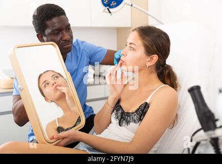 Esthéticienne examinant le visage de la patiente avant la procédure de cosmétologie du sourit et de l'augmentation des lèvres Banque D'Images