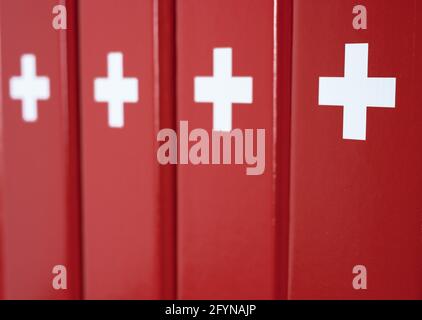 Dossiers rouges avec une croix blanche - imitation d'un drapeau suisse dans un environnement de bureau Banque D'Images